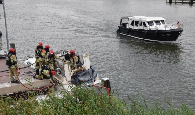 De brandweer druk bezig met het blussen van de brand op de motorboot.