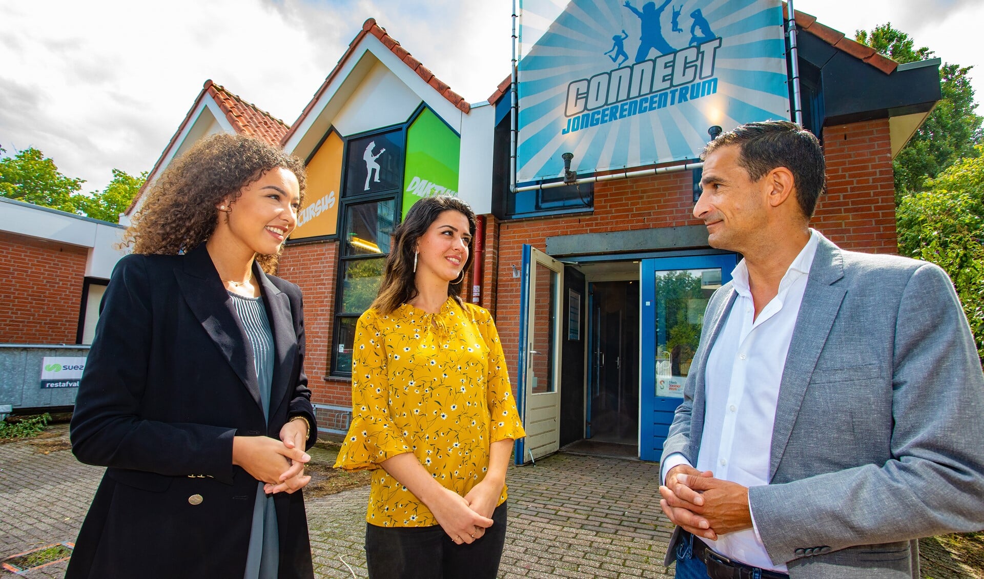 Budgetcoaches Nathalie (l) en Talar met wethouder Maarten Hoelscher bij jongerencentrum Connect.