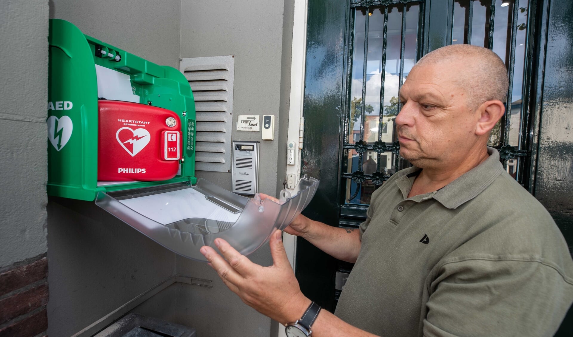 Ed Bakker toont de AED, die sinds vorige week bij De Geus hangt.