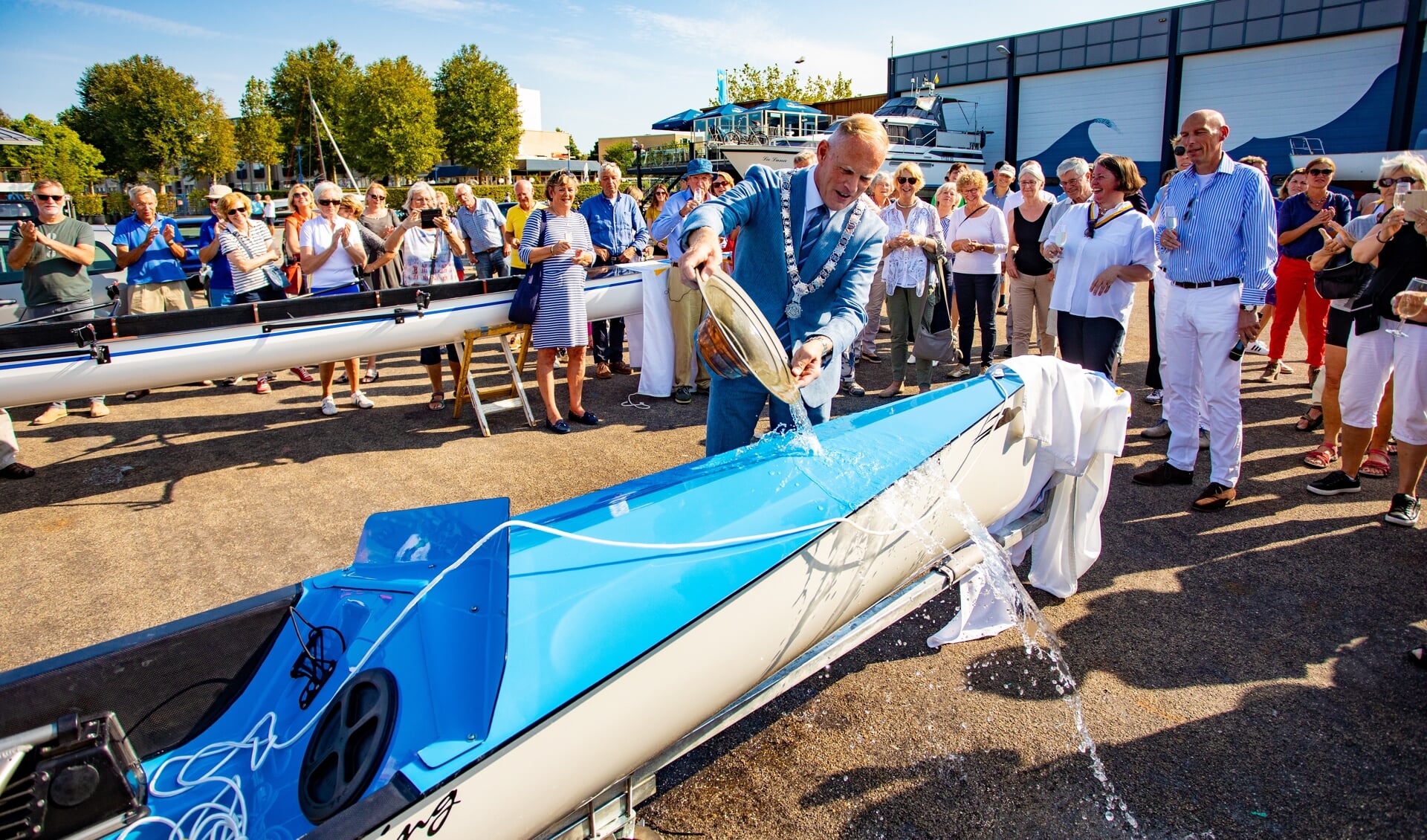 Burgemeester Han ter Heegde van Gooise Meren doopt de nieuwe roeiboot in Huizen.