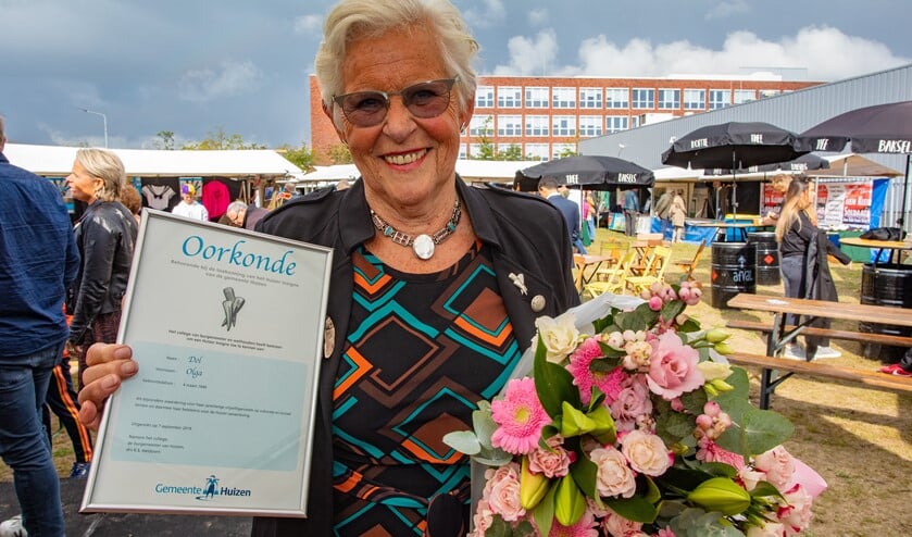 Trots toont Olga de oorkonde en de bos bloemen die ze kreeg bij het Huizer Insigne.