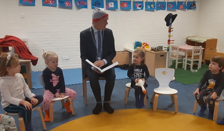 Burgemeester Niek Meijer leest met een slaapmuts op voor aan de kinderen bij Peuterschool 't Startbloek.