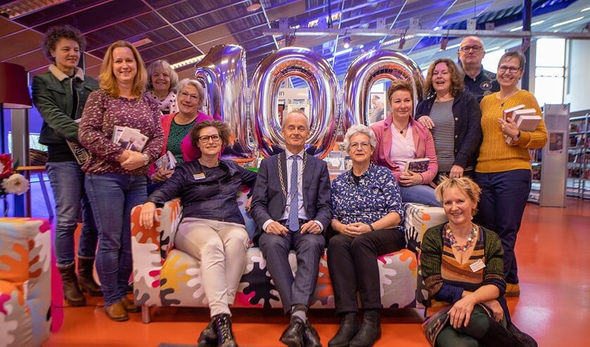 Burgemeester Niek Meijer tussen het personeel van de jubilerende bibliotheek in Huizen. Links van hem Pauline Gmelig Meyling en rechts Jacqueline Straathof.