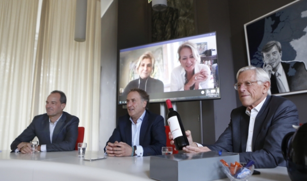 <p>Wethouder Stam toont te gewonnen fles wijn aan winnares Lisette.</p>