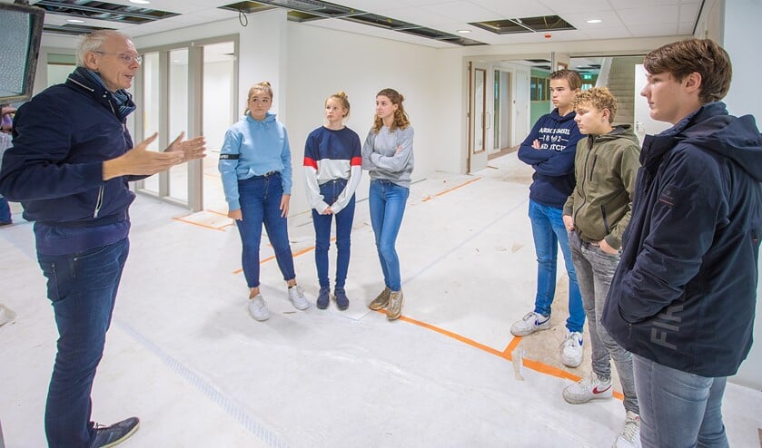 Conciërge Harry geeft een klein groepje leerlingen een exclusieve rondleiding in het nieuwe gebouw van het Erfgooiers College.