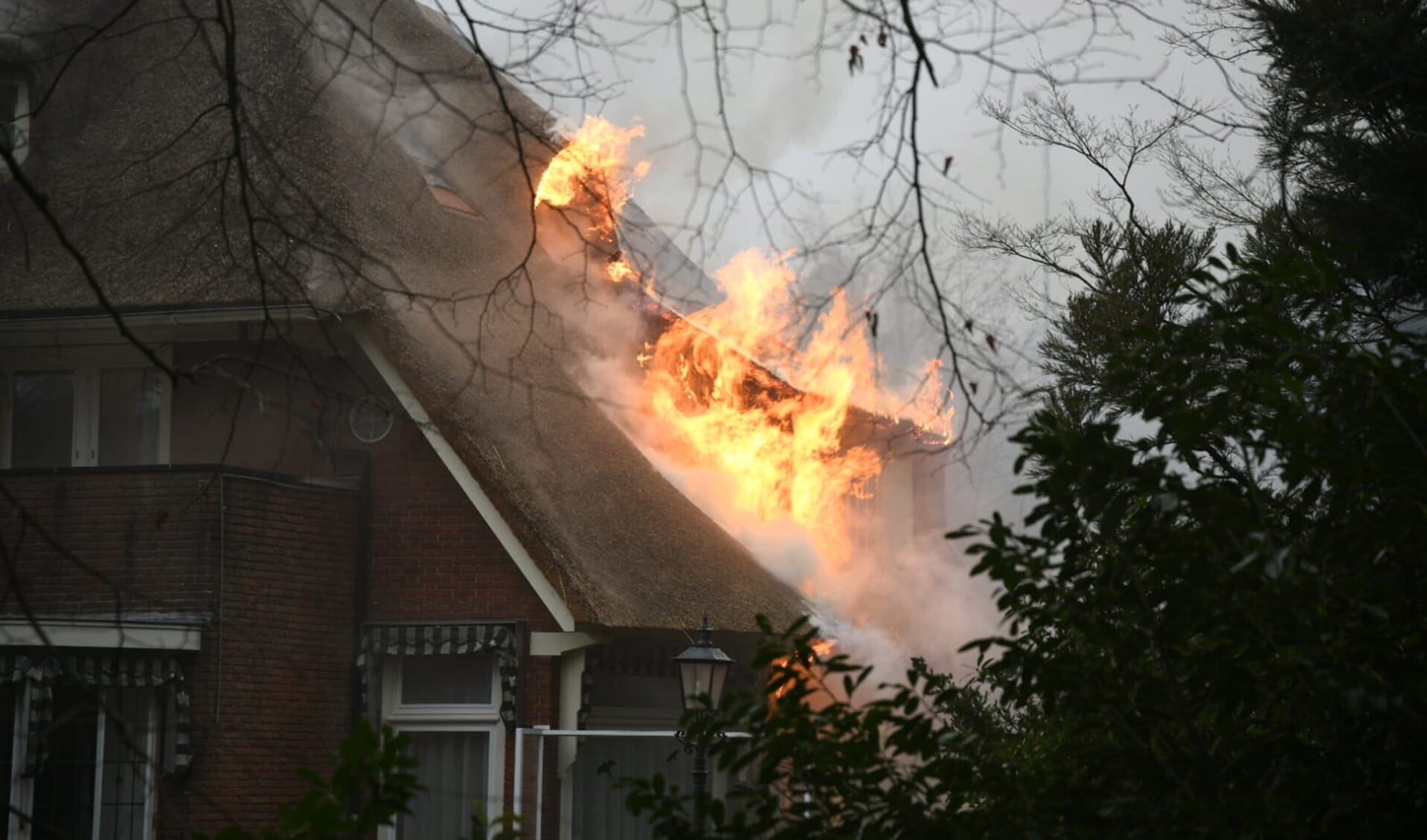 De vlammen slaan uit het dak bij de villa met rieten kap.