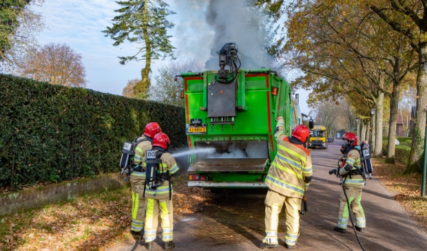 <p>De brandweer probeert de brand in de vuilcontainerwagen te blussen.</p>