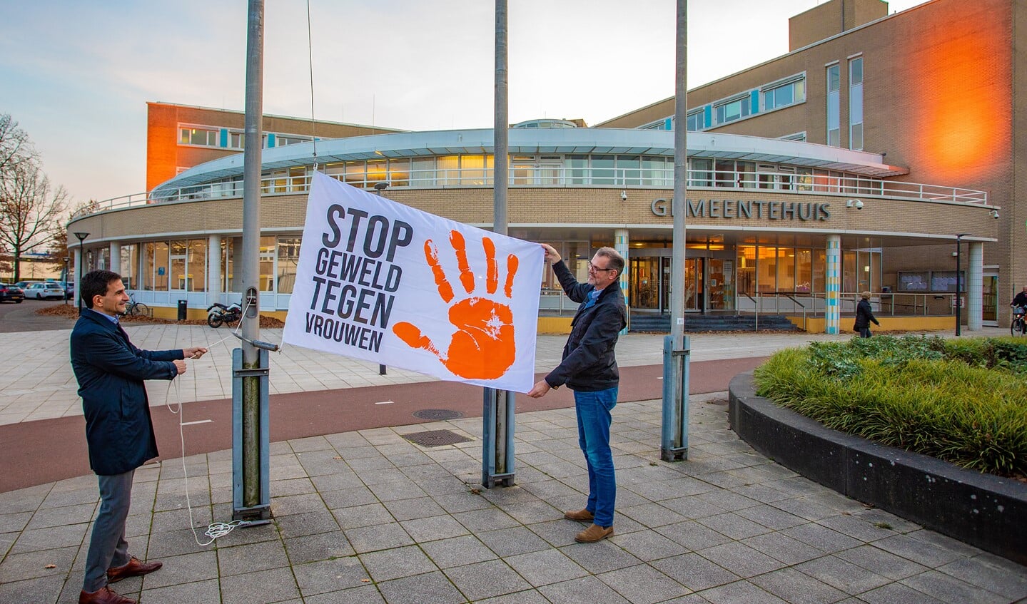 Wethouder Maarten Hoelscher (l) met de vlag en het oranje uitgelichte gemeentehuis op de achtergrond.