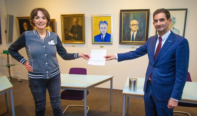 <p>Sylvia Slegers van de actiegroep overhandigt de petitie aan wethouder Maarten Hoelscher.</p>