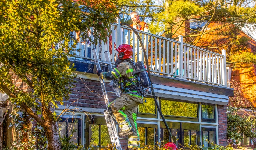 De brandweer inspecteert het dakbeschot bij het balkon.