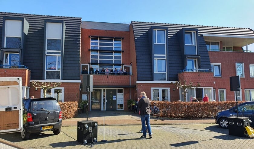 De zanger zingt op veilige afstand voor de bewoners.