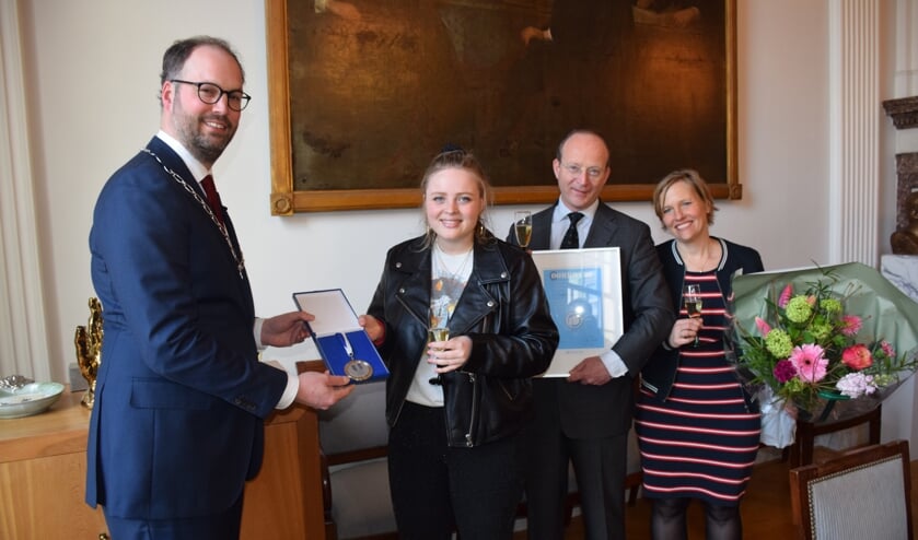 Loco-burgemeester Léon de Lange reikt het Jeugdlintje uit aan Sophia Kruithof. Naast haar staan haar ouders Harald en Marije.