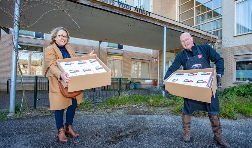 Personeel van Voor Anker neemt op gepaste afstand de koeken in ontvangst van Jan Koelewijn van 't Stoepje.
