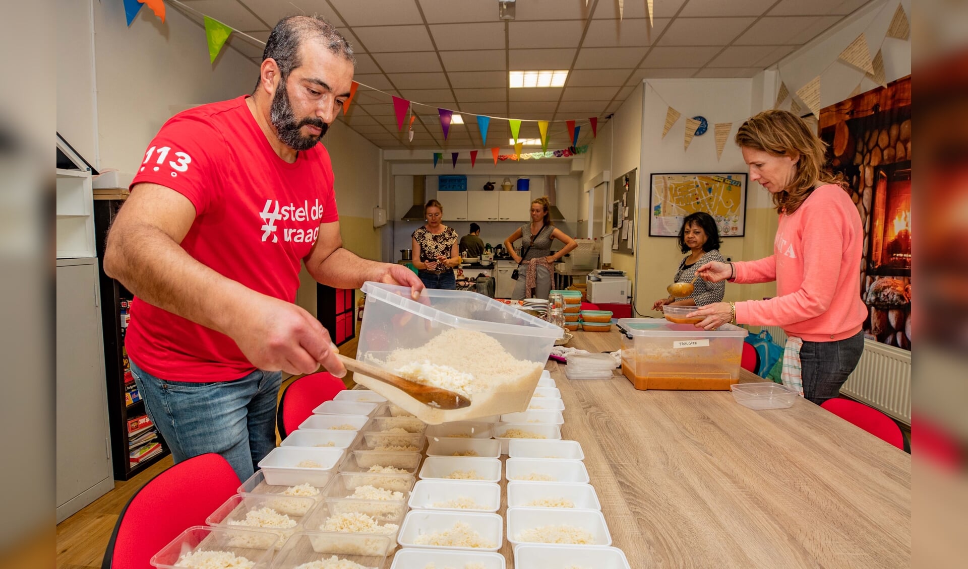 Ahmed Turkmen en Anne van Roy verdelen het eten in 45 bakjes. 
