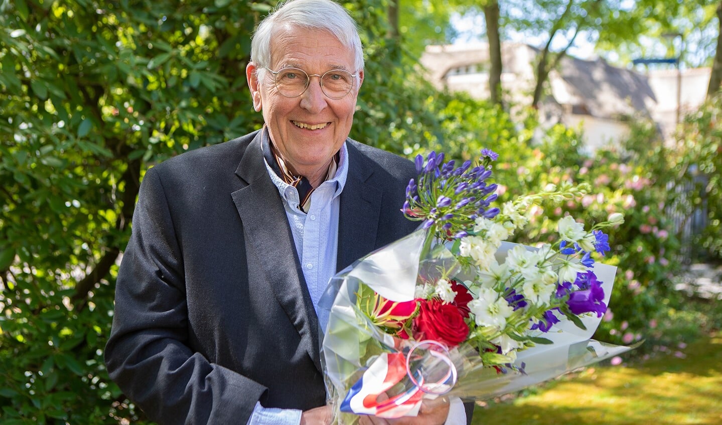 Teun Koetsier met zijn bloemen, die hij kreeg uit handen van de burgemeester vanwege zijn koninklijke onderscheiding.