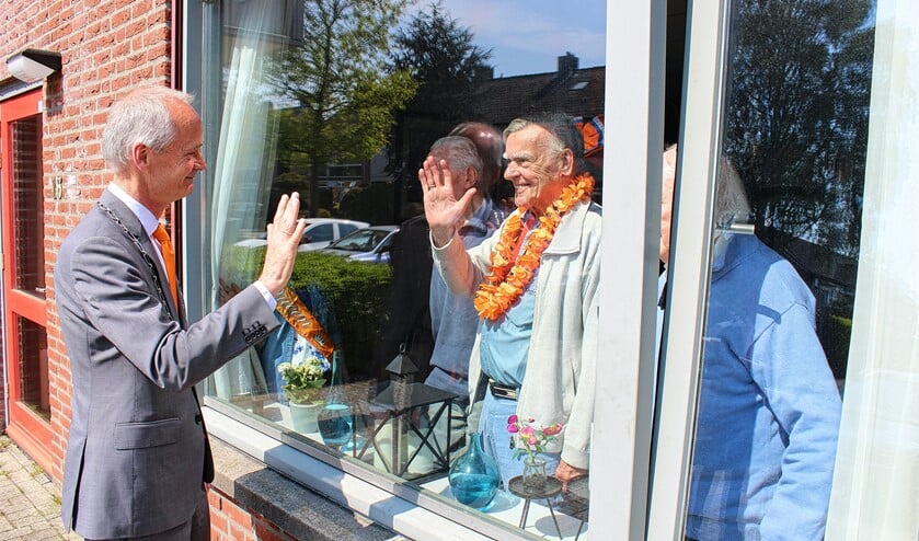 Burgemeester Niek Meijer zwaait naar bewoners.