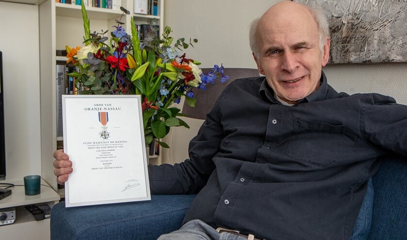 Joan van Haaften met zijn kopie van de oorkonde en bos bloemen die hij kreeg vanwege zijn onderscheiding.