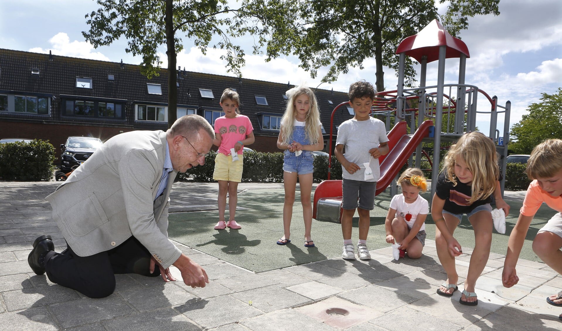 Wethouder Theo Reijn knikkerde met de kinderen, die een zakje knikkers cadeau hebben gekregen van de gemeente.