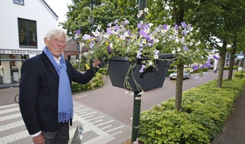 Wethouder Ton Stam bevestigt één van de hanging baskets in het centrum van Laren.