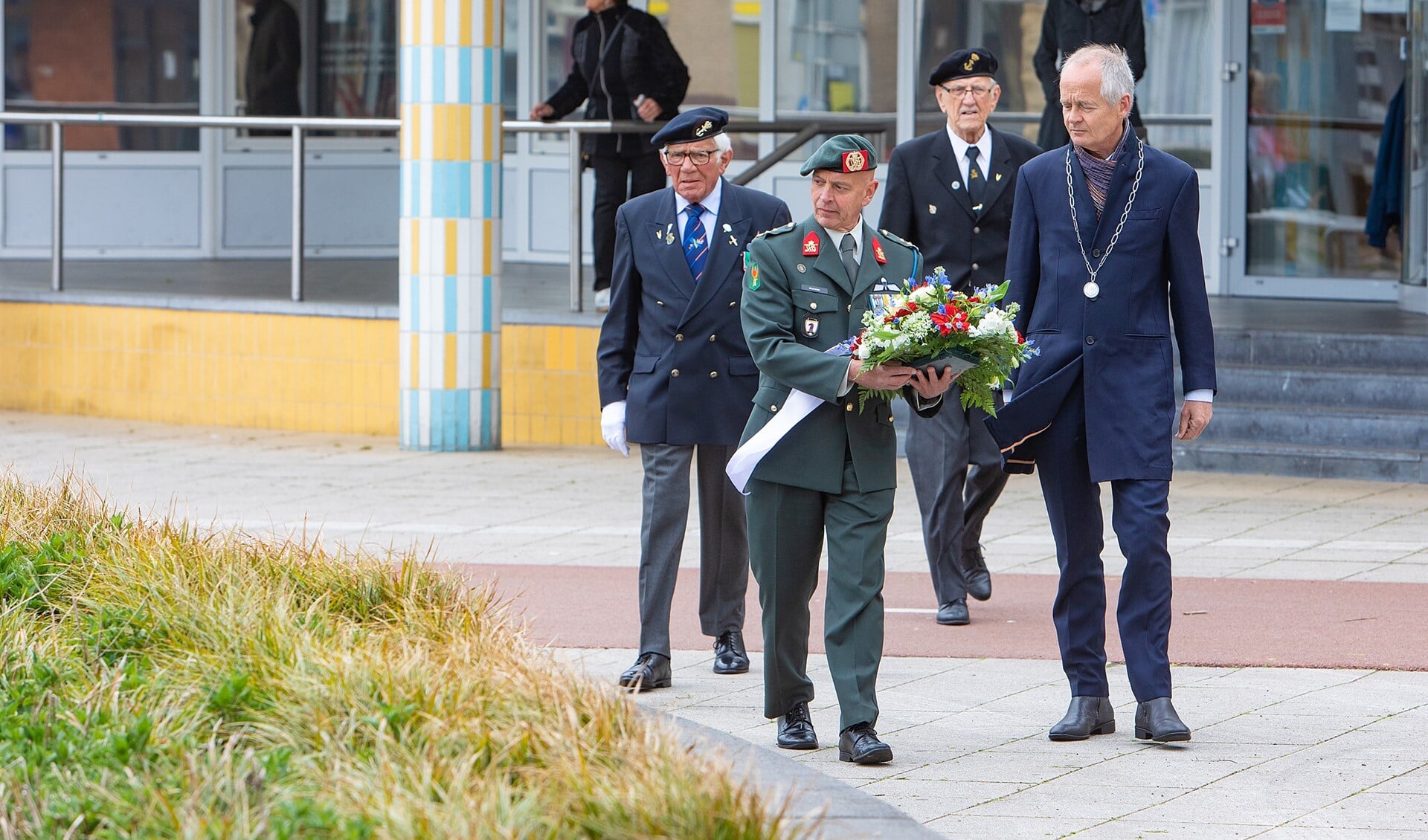 Veteranen leggen samen met de burgemeester bloemen neer bij het monument.