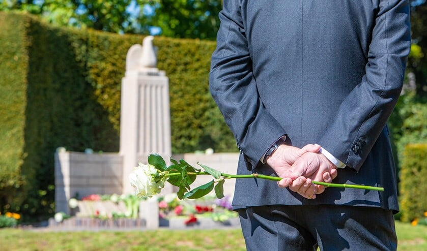 Iemand wacht tot hij bloemen neer kan leggen bij het herdenkingsmonument in Blaricum.