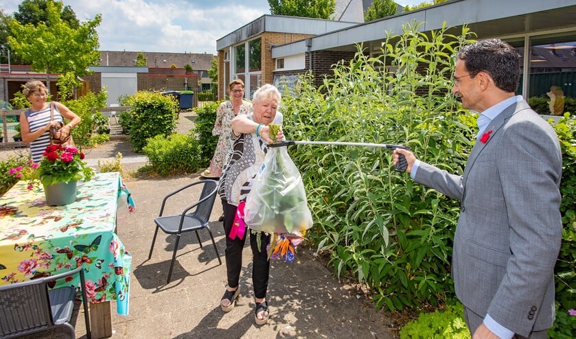 Wethouder Maarten Hoelscher gaf naast de strippenkaart ook op veilige afstand een bos bloemen aan Riet.