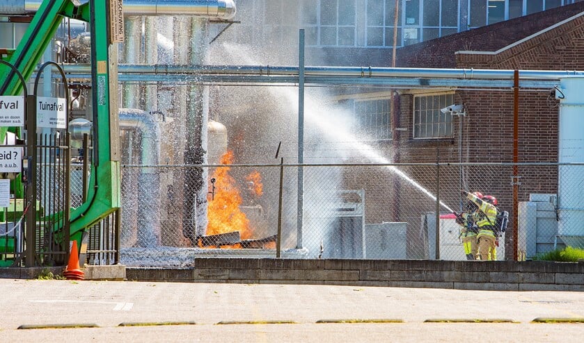 De brandweer dekt de machine en brandende olie af met schuim.