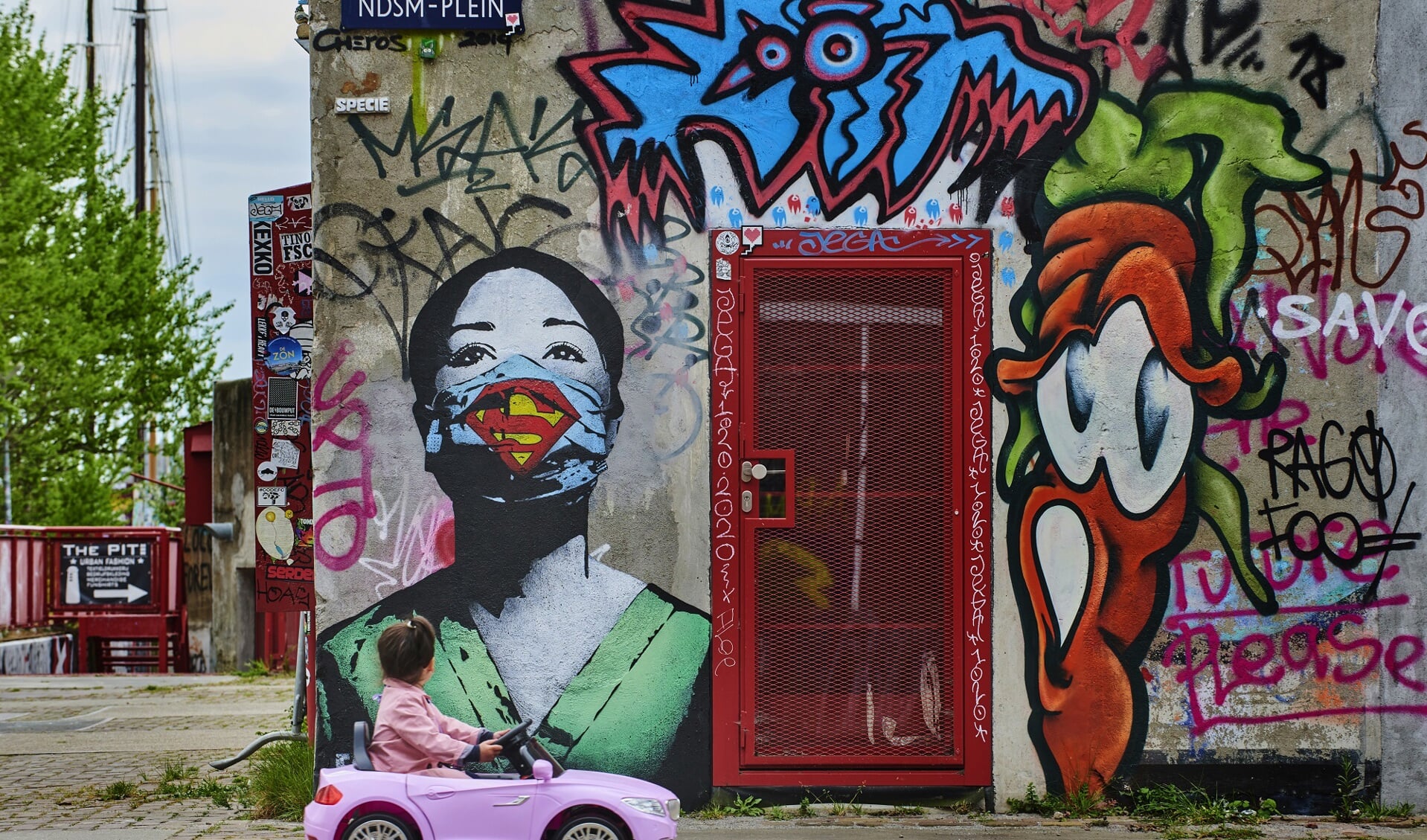 Graffitti art gemaakt door FAKE van een verpleegster op het NDSM plein in Amsterdam. Een klein meisje kijkt toe.