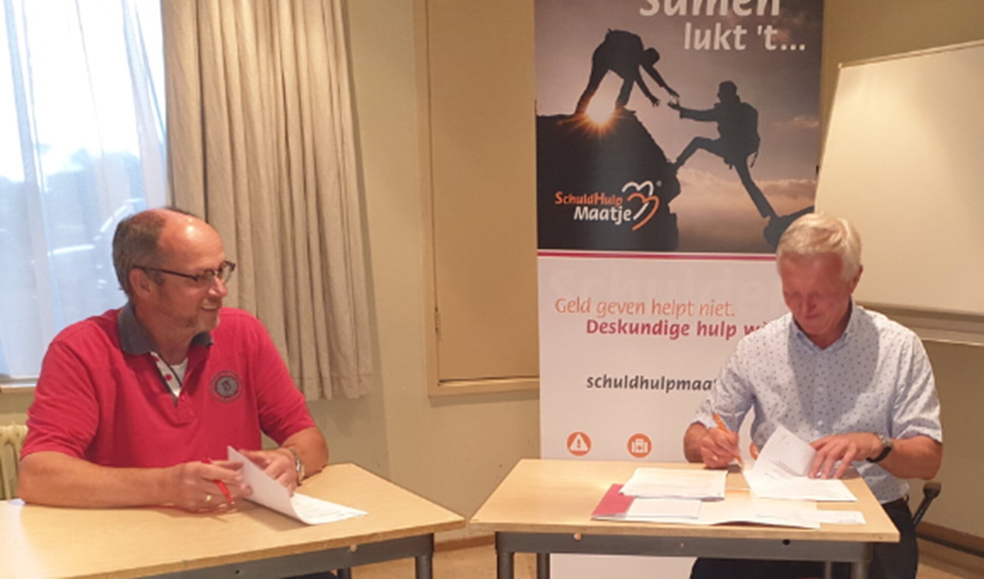 Jan Otter (l) en Gerard Barmentlo ondertekenen de overeenkomst met SchuldHulpMaatje Nederland.