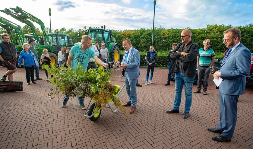 Wethouder Theo Reijn krijgt een lading ongewenst groen uit de bermen overhandigd van de boeren.