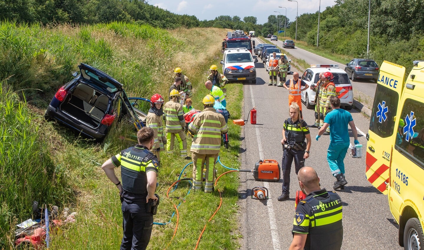 Hulpverleners ontfermen zich over de bestuurster die met haar auto uit de bocht was gevlogen.
