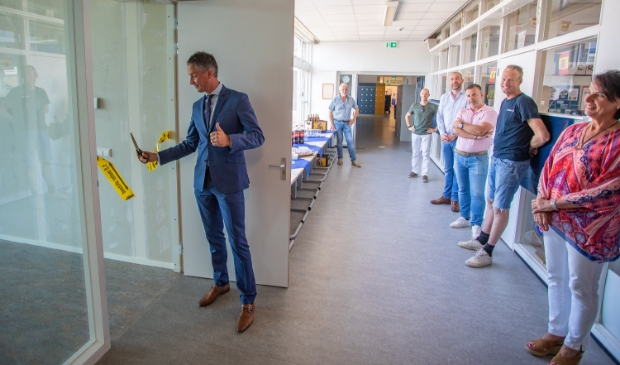Bart van den Haak knipt het lint door in aanwezigheid van de bouwers en rector Loes IJkelenstam.