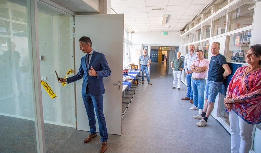 Bart van den Haak knipt het lint door in aanwezigheid van de bouwers en rector Loes IJkelenstam.