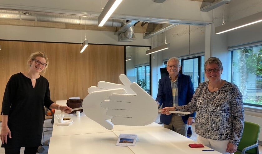 Anne Oosterbaan (l) van de Alliantie, Sytze Haenen en Jacobien Middelkoop feliciteren elkaar op 1,5 meter met de overeenkomst.