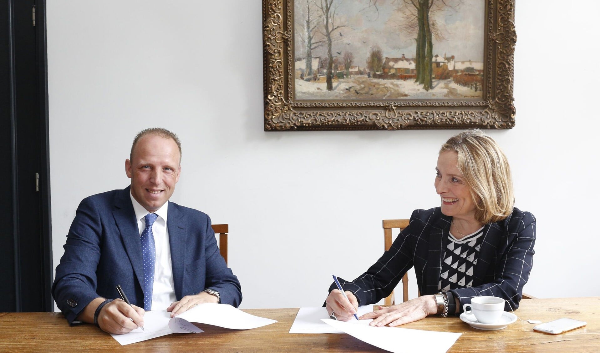 Wethouder Karin van Hunnik (r) tekent de stukken.