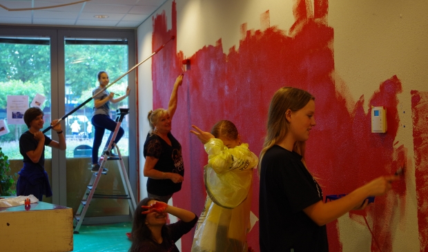 De jongeren schilderen een van de muren rood, een kleur die in het hele wijkcentrum terugkomt.
