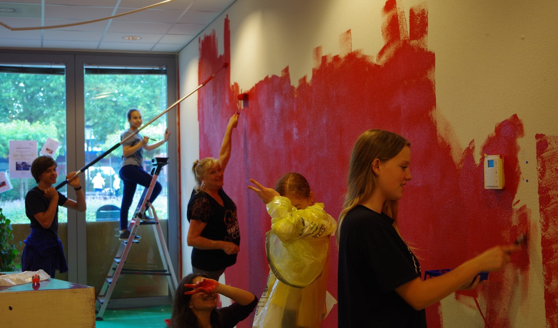 De jongeren schilderen een van de muren rood, een kleur die in het hele wijkcentrum terugkomt.