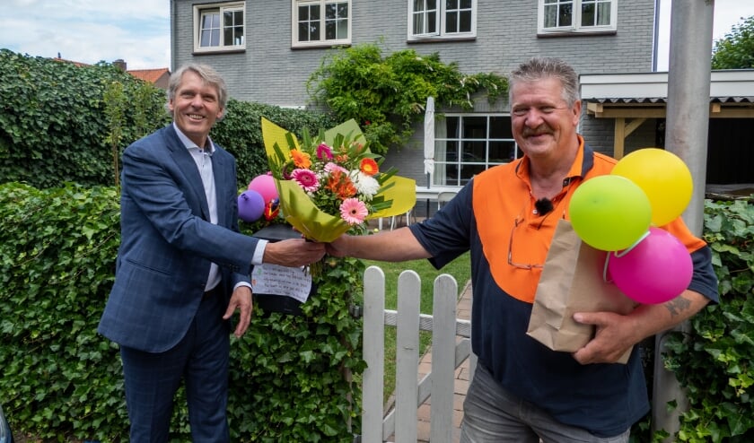 Wethouder Nico Schimmel overhandigt de bos bloemen aan postbode Peter Bakker