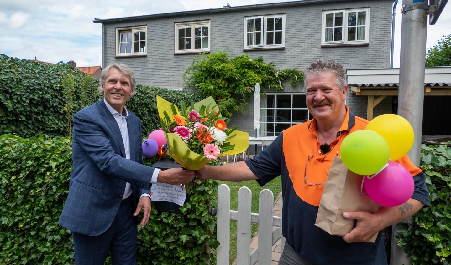 Wethouder Nico Schimmel overhandigt de bos bloemen aan postbode Peter Bakker