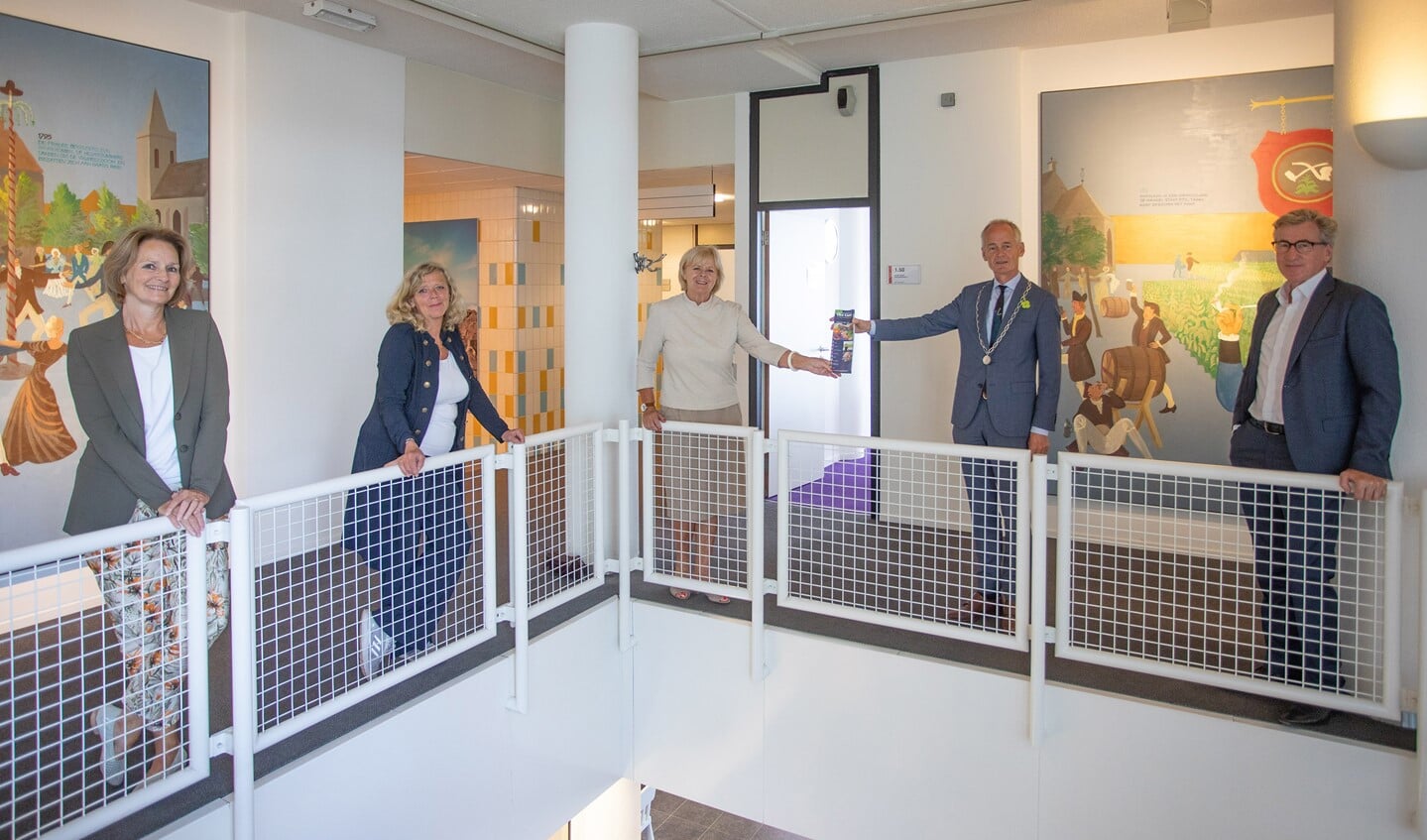 Keurig op 1,5 meter afstand wordt het nieuwe programma overhandigd aan de burgemeester.