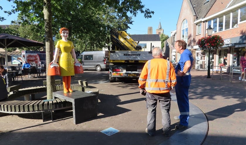 De heren die het beeld hebben geplaatst, inspecteren hun werk.