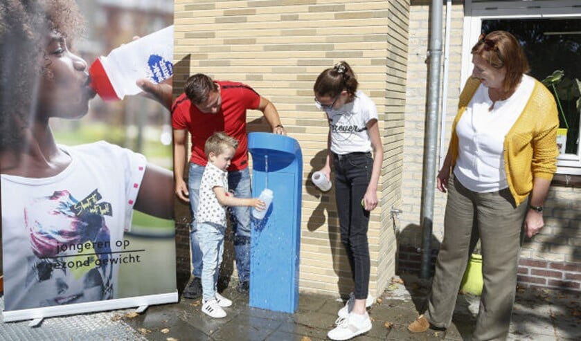 <p>Wethouder Wilma de Boer-Leijsma kijkt toe hoe de leerlingen water tappen uit het tappunt.</p>