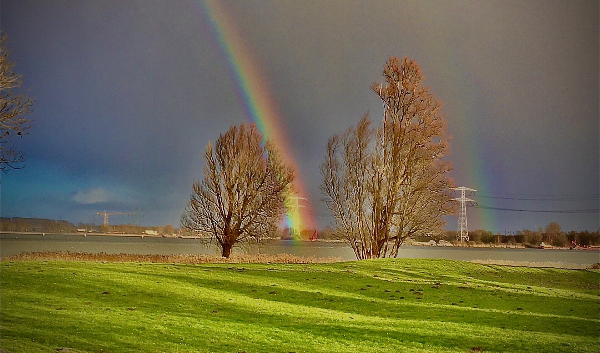 Een dubbele regenboog te zien vanaf het strand in Muiderberg.