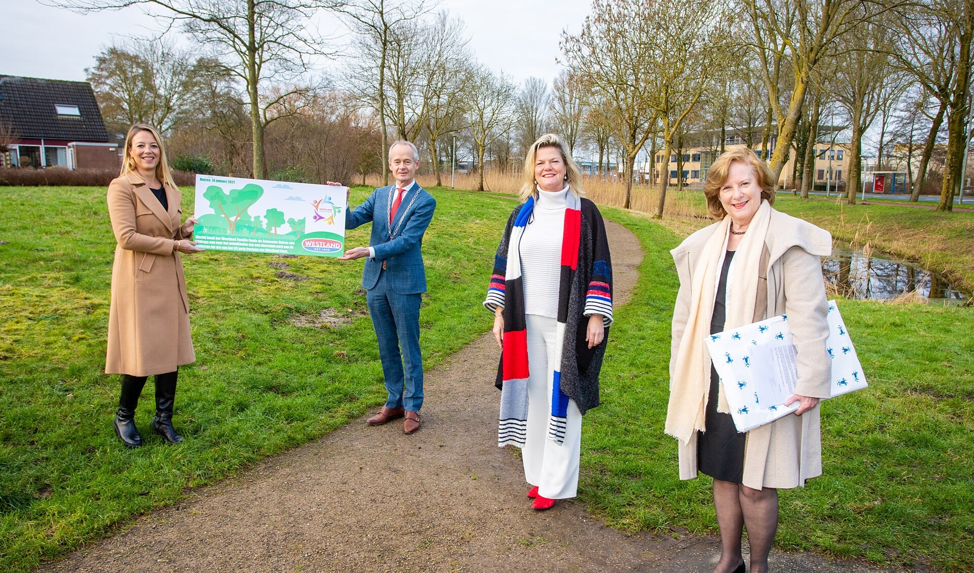 Marjolein Schuyt (l) overhandigt burgemeester Niek Meijer het Westlandpark symbolisch onder toeziend oog van CEO Henny Westland en wethouder Marlous Verbeek (r).