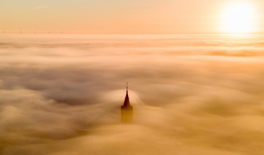 <p>Het topje van de Grote Kerk van Naarden stak nét boven de mist uit.</p>