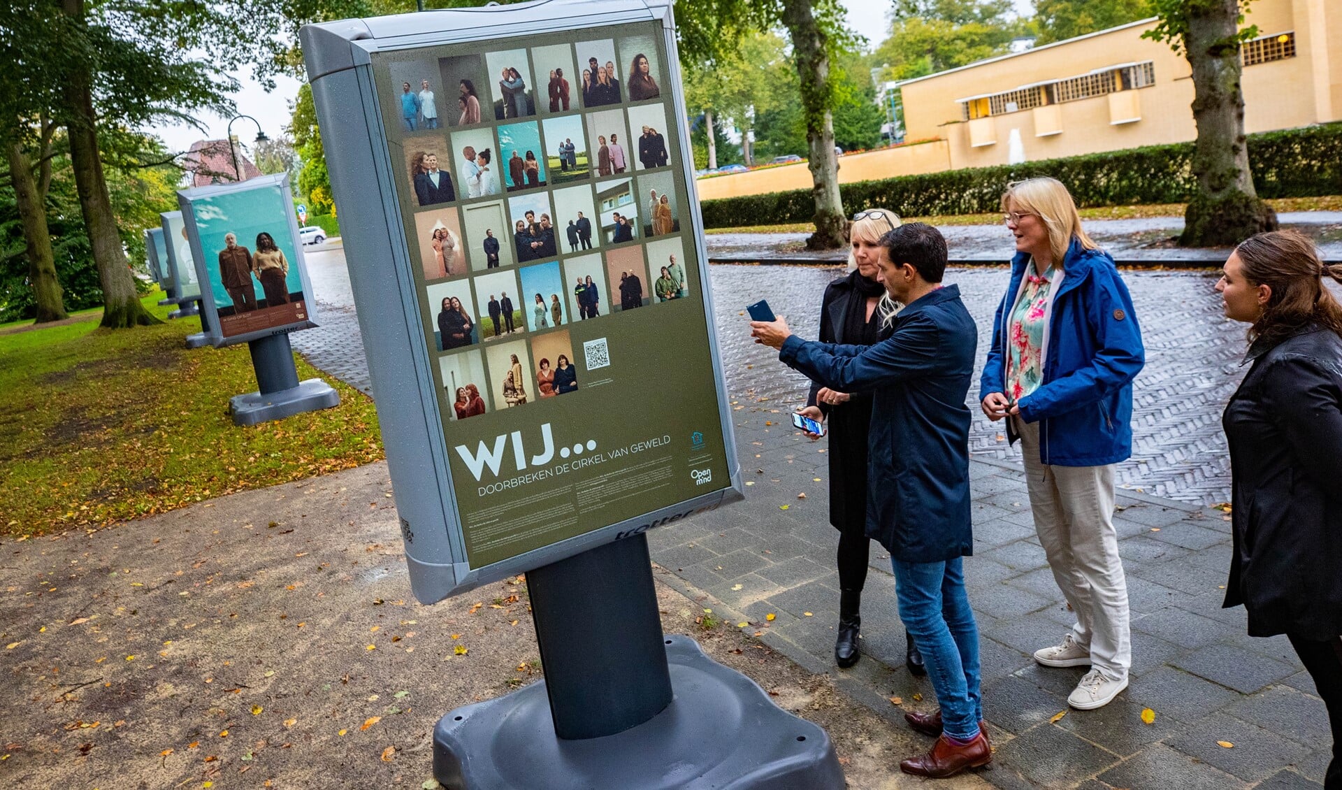 Maarten Hoelscher (met telefoon in de hand) en zijn Hilversumse collega Karin Walters (blauwe jas) openden dinsdag de tentoonstelling 'Wij...doorbreken de cirkel van geweld' in het Dudokpark.