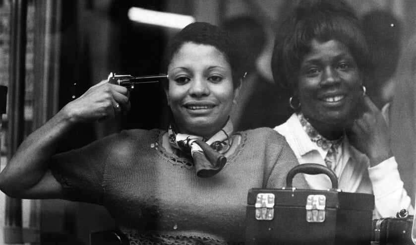 <p>Vrouw met een speelgoedpistool tegen haar hoofd achter het raam van een café op de Rotterdamse West-Kruiskade, 1969</p>