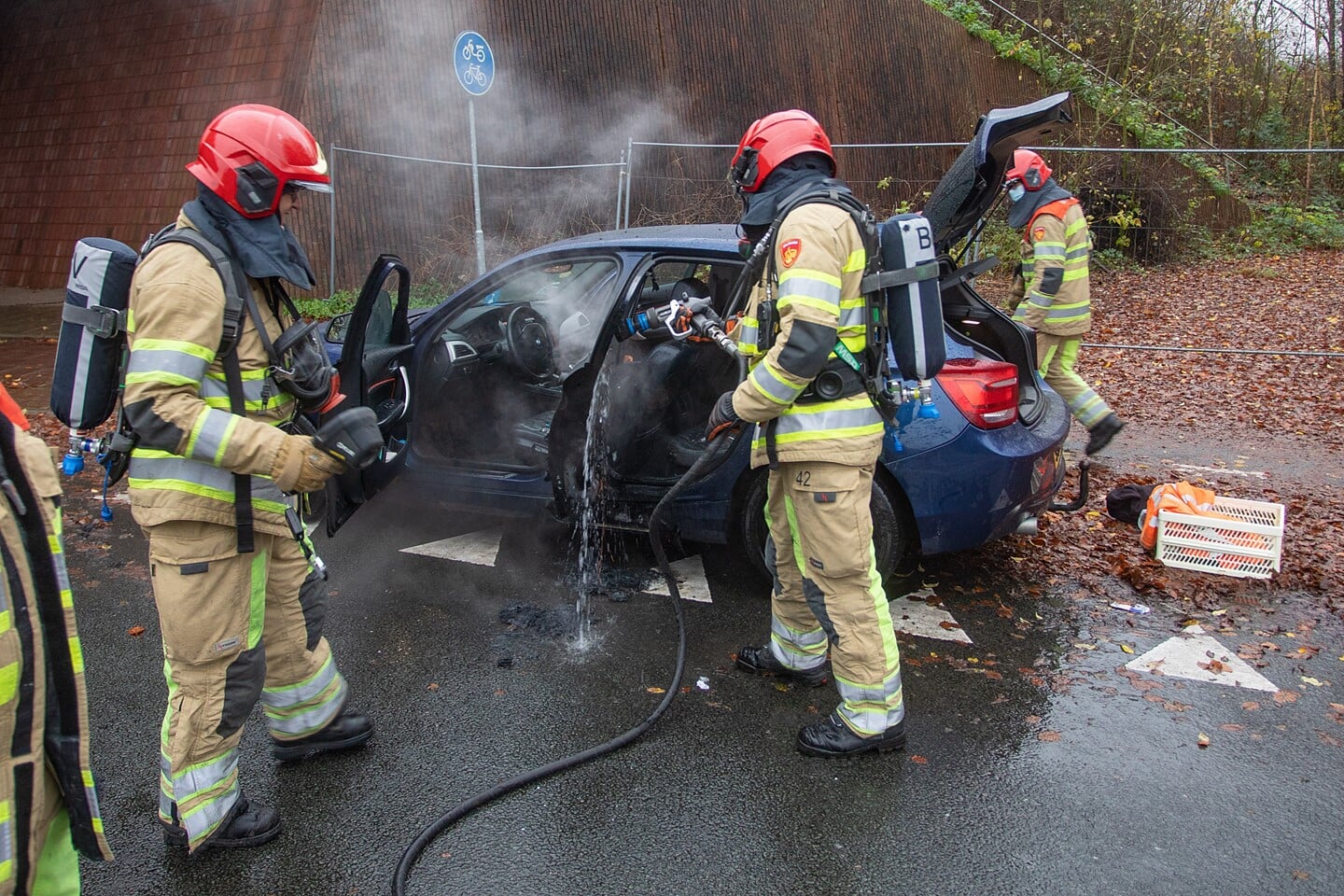 De brandweer blust de deur waar de brand vermoedelijk is ontstaan.