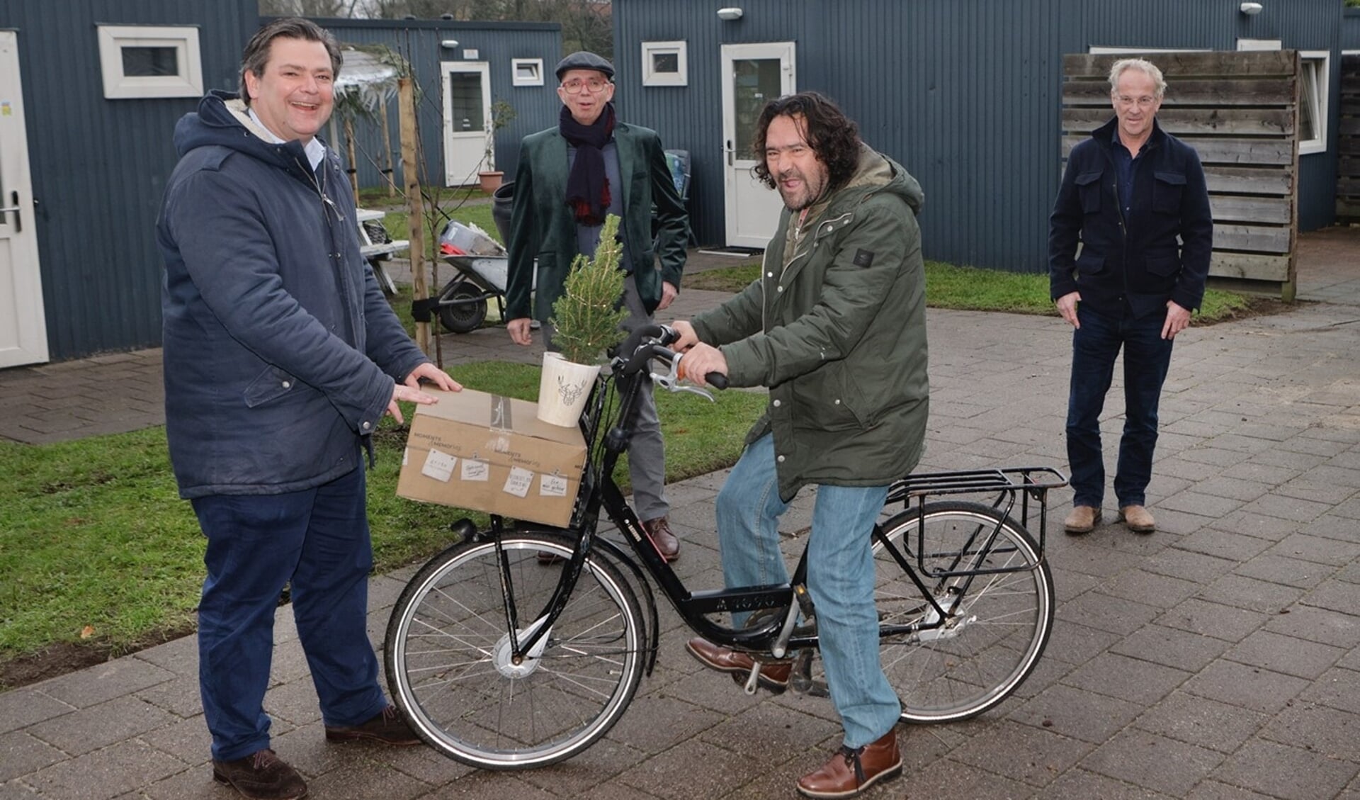 Wethouder Floris Voorink deelt samen met Maarten van Gessel van Het Gooi en Omstreken en Harro Koeleman van Kwintes kerstpakketten en een kerstboompje uit aan de bewoners van Keerpunt-Zuid.