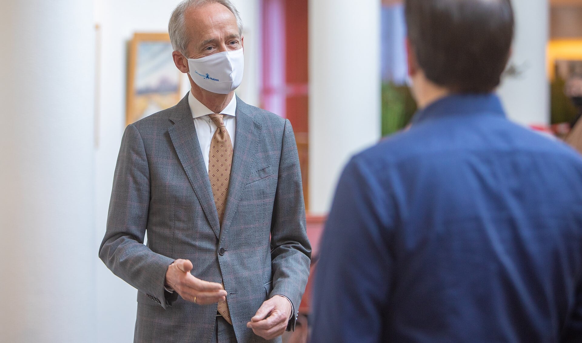 Burgemeester Niek Meijer spreekt in de gang van het gemeentehuis met een medewerker.